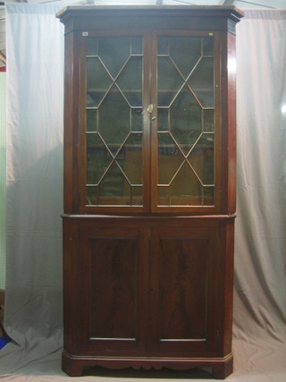 A Georgian mahogany double corner cabinet, the upper section with moulded cornice with shelved interior enclosed by astragal glazed panelled doors, the base fitted cupboards enclosed by panelled doors, raised on bracket feet 48"