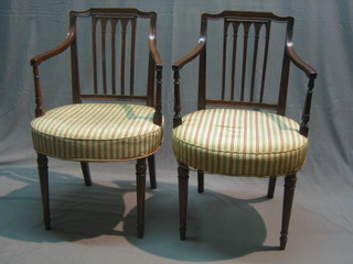 A pair of 19th Century Hepplewhite style mahogany open arm, stick and rail back carver chairs, with upholstered seats raised on turned supports