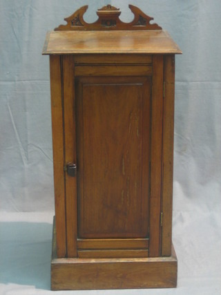 An Edwardian walnut pot cupboard with carved raised back enclosed by panelled doors, raised on a platform base 14"