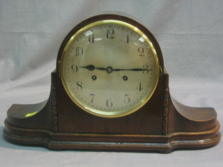 A striking mantel clock with silvered dia l and Arabic numerals contained in an oak Admiral's hat shaped case