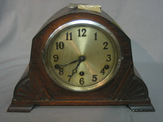 A chiming mantel clock with silvered dial and Arabic numerals contained in an oak arch shaped case