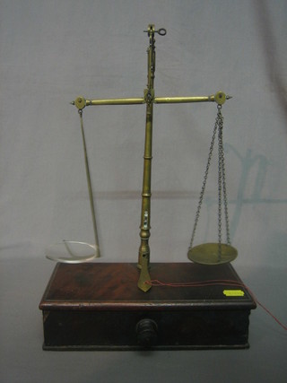 A Victorian gold balance raised on a mahogany base fitted a drawer