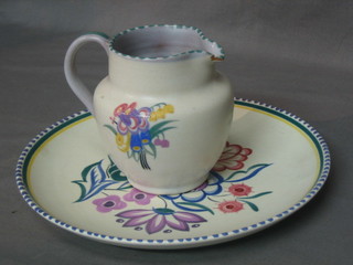 An Adams Poole Pottery jug with floral decoration (chip to spout), base with impressed mark 4" and a later circular Poole Pottery plate base with Dolphin mark 9"