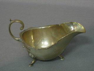 A silver sauce boat with wavy border and C scroll handle raised on 3 hoof feet, Birmingham 1911 3 ozs