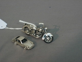 A modern silver miniature model of a motorcycle and 1 other of a motor car (2)