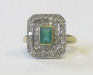A gold dress ring set a rectangular emerald surrounded by numerous diamonds