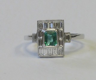 A lady's 18ct white gold dress ring set a rectangular cut emerald supported by baguette cut diamonds, approx