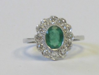 A lady's 18ct white gold dress ring set an oval cut emerald surrounded by diamonds, approx 0.60/1ct