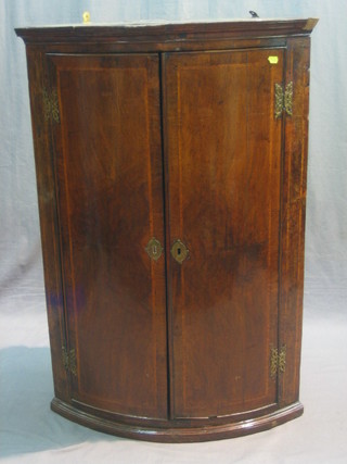 A Georgian mahogany bow front hanging corner cabinet, the interior fitted shelves enclosed by panelled doors 27"
