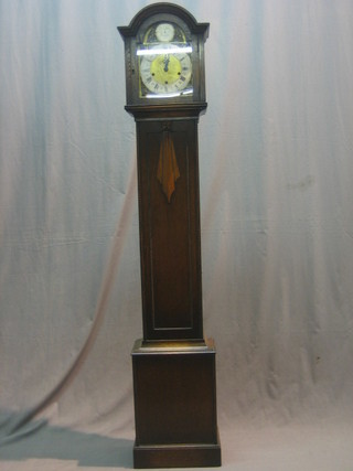 A 1930's chiming Granddaughter clock with 7 1/2" arched dial with silvered chapter ring, contained in an oak case with sliding hood, 66"