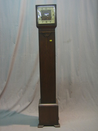 A 1930's Granddaughter clock, the square dial with silvered chapter ring and Arabic numerals, contained in an oak case 56"