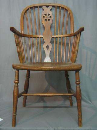 An 18th/19th Century elm stick and wheel back Windsor chair with solid seat, raised on turned supports with X framed stretcher