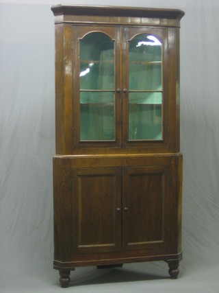 A 19th Century Country oak double corner cabinet, the upper section fitted shelves enclosed by glazed panelled doors, the base fitted a cupboard enclosed by a panelled door