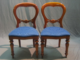 A set of 8 Victorian style mahogany balloon back dining chairs with carved mid rails and upholstered seats, raised on turned and reeded supports