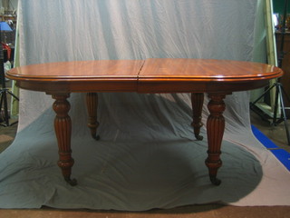 A Victorian style mahogany extending dining table, raised on turned and reeded supports together with 3 extra leaves