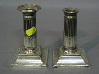 A pair of Edwardian silver reeded candlesticks with Doric capitals, raised on square bases 5", Sheffield 1900 (1 with missing sconce)