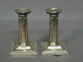 A pair of Victorian silver candlesticks with detachable sconces and swag decoration, raised on square bases, London 1896, 5"