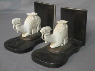 A pair of carved ivory and ebony book ends in the form of seated camels