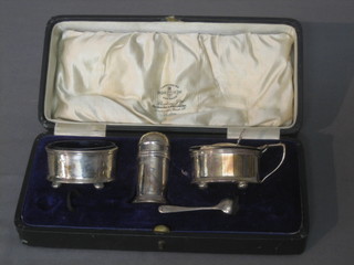 A silver 3 piece condiment set comprising mustard, pepper and salt together with 1 spoon, Birmingham 1944, cased