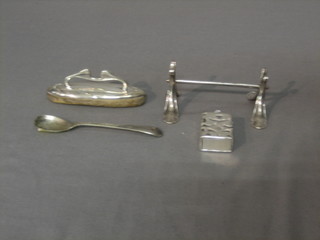 A silver knife rest, a silver nail buffer, a small glass bottle contained in a pierced white metal case and silver plated mustard spoon