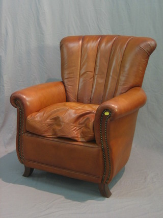 A modern mahogany framed and brown leather armchair with scrolled arms and raised on scrolled supports