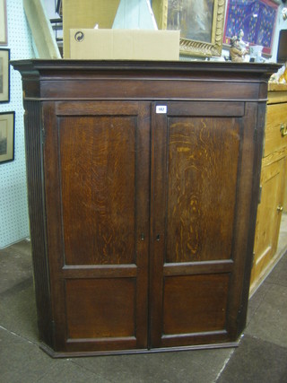 A 19th Century oak hanging corner cabinet with moulded cornice, the interior fitted 3 shelves, the base fitted 4 spice drawers enclosed by panelled doors 36"