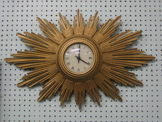 A 1930's Sunburst wall clock with paper dial and Roman numerals, contained in a carved wooden case and with later battery operated movement