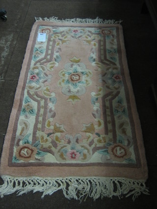 A small peach ground and floral patterned Chinese rug 48" x 24"