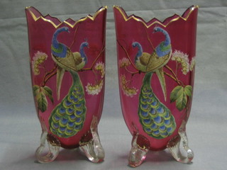 A pair of Victorian cranberry coloured glass vases with enamelled decoration, decorated birds amidst branches raised on 3 scrolled feet 10"