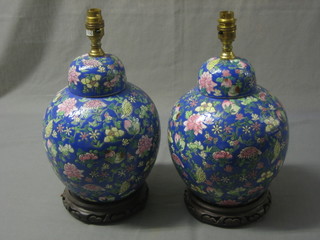 A pair of Oriental style table lamps in the form of ginger jars and covers, raised on hardwood stands 13"