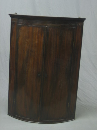 A Georgian mahogany bow front corner cabinet fitted shelves and enclosed by panelled door, 29"