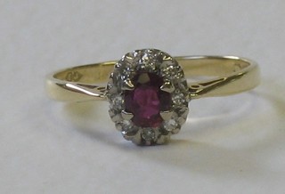 An 18ct gold dress ring set a red stone surrounded by diamonds