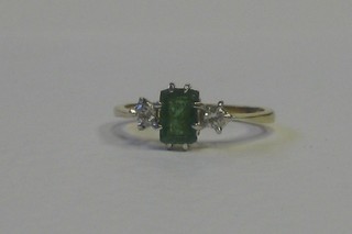 A lady's gold dress ring set a  square cut emerald supported by diamonds