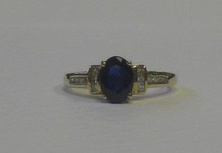 A lady's gold dress ring set an oval cut sapphire supported by diamonds