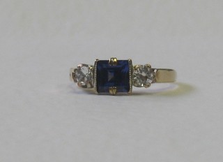 A lady's gold dress ring set a square cut sapphire supported by 2 diamonds