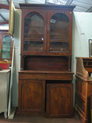A Victorian mahogany bookcase on cabinet, the upper section fitted shelves enclosed by arch panelled doors, the base fitted a recess above 1 long drawer and double cupboard enclosed by arch panelled doors, raised on a platform base 42"