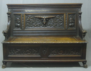 A Victorian carved oak settle with raised back, the seat with hinged lid, raised on hoof feet, 59"