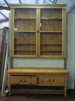 A Victorian stripped and polished pine raised dresser back with moulded cornice, fitted a cupboard enclosed by glazed panelled doors, raised on a cut down base with later top fitted 2 drawers above a recess  60"