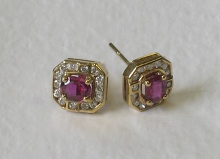 A pair of 18ct gold ear studs set circular cut red stones surrounded by diamonds