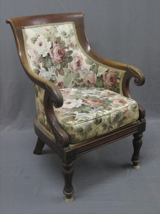 A William IV mahogany showframe armchair upholstered in floral material raised on turned supports