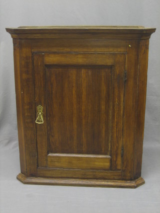 A 18th/19th Century oak hanging corner cabinet, the interior fitted shelves enclosed by a panelled door 31"