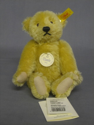 A reproduction 1927 Steiff yellow teddy bear with articulated limbs 9" complete with carrier bag