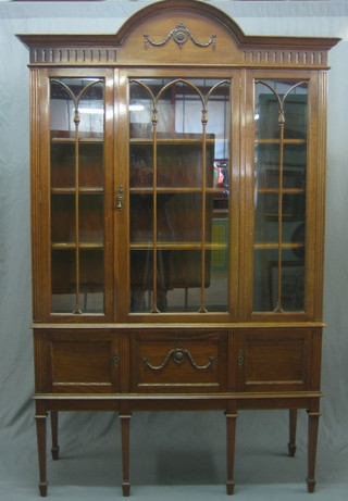 An Edwardian walnut Chippendale style display cabinet with arch shaped cornice, the interior fitted adjustable shelves enclosed by astragal glazed doors, the base fitted cupboards enclosed by panelled doors, raised on square fluted supports ending in spade feet 51"