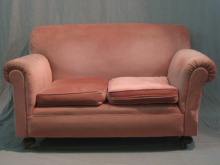 An Edwardian mahogany framed drop arm 2 seat settee upholstered in pink material, raised on turned supports 58" 