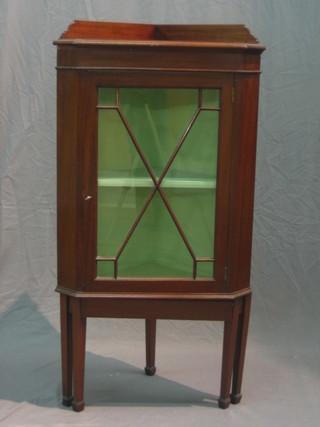 An Edwardian mahogany corner cabinet with raised back, fitted shelves enclosed by an astragal glazed panelled door, on square supports ending in spade feet