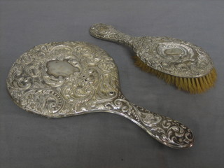 An embossed silver backed hand mirror together with a hairbrush (holes and dents)