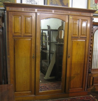 A Victorian  walnut wardrobe with moulded cornice, the centre section fitted 3 trays above 3 long drawers enclosed by arched panelled door, flanked by a pair of cupboards on a platform base 81"