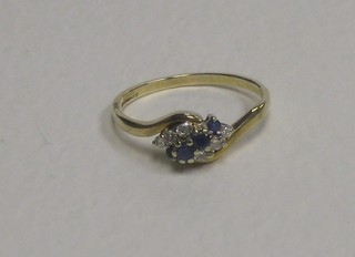A 9ct gold crossover dress ring set 3 sapphires and supported by 6 diamonds