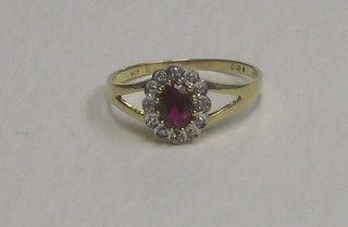 A gold dress ring set an oval red coloured stone supported by diamonds