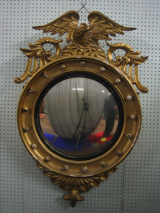 A Regency circular convex plate wall mirror contained in a circular gilt ball studded frame surmounted by an eagle, 23"